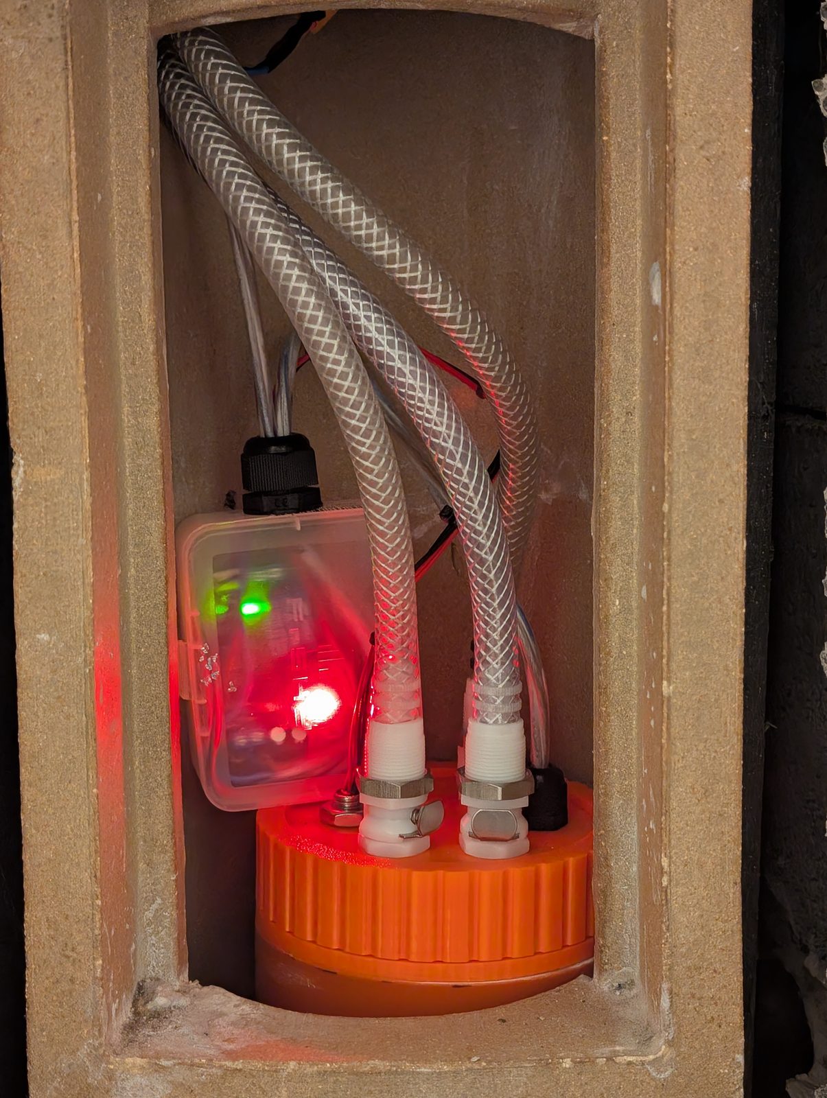 The sump installed at the bottom of the chimney, hoses connected, controller glowing beside it