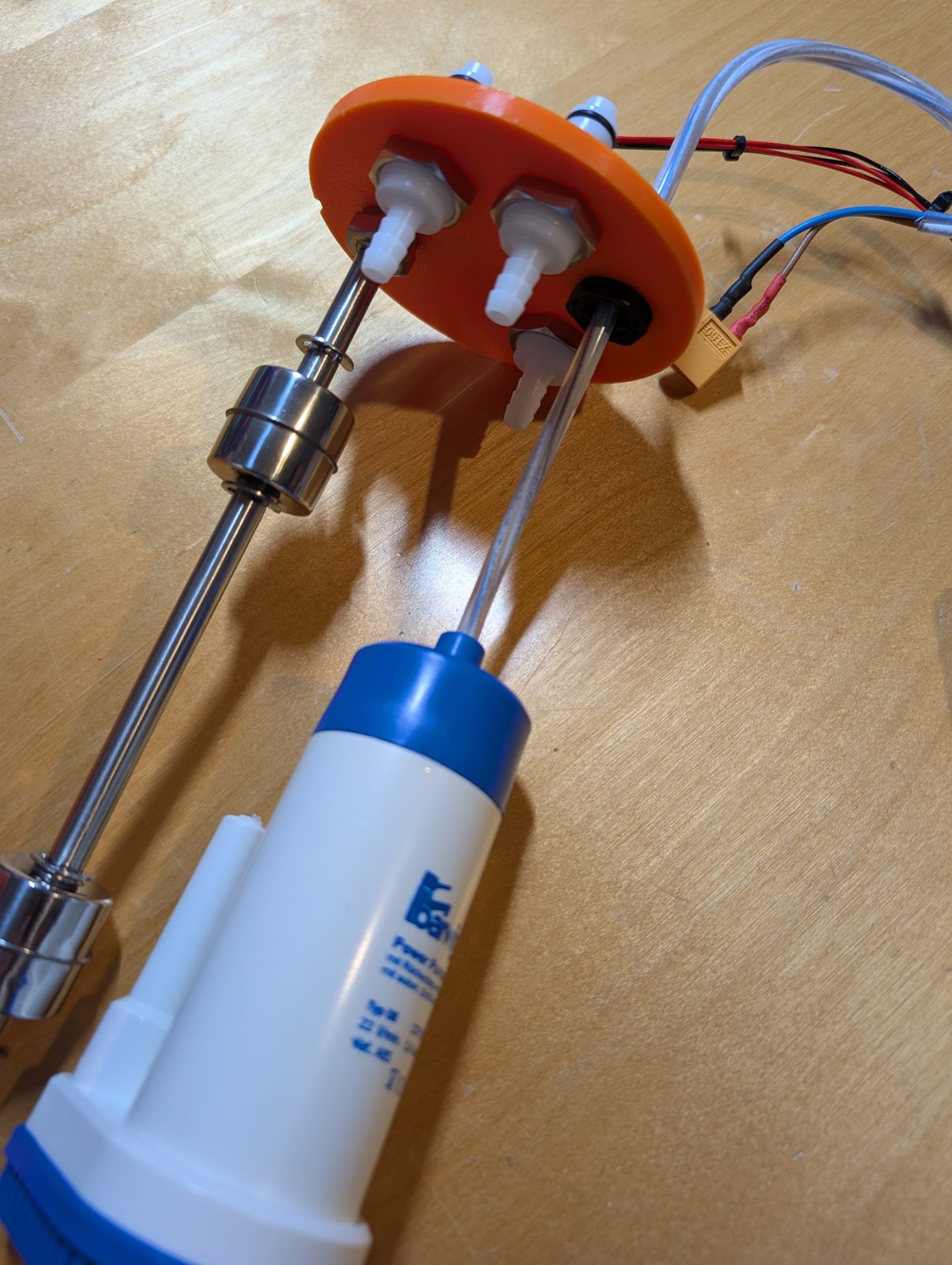 The lid seen from the inside, pump and float switch hanging from it
