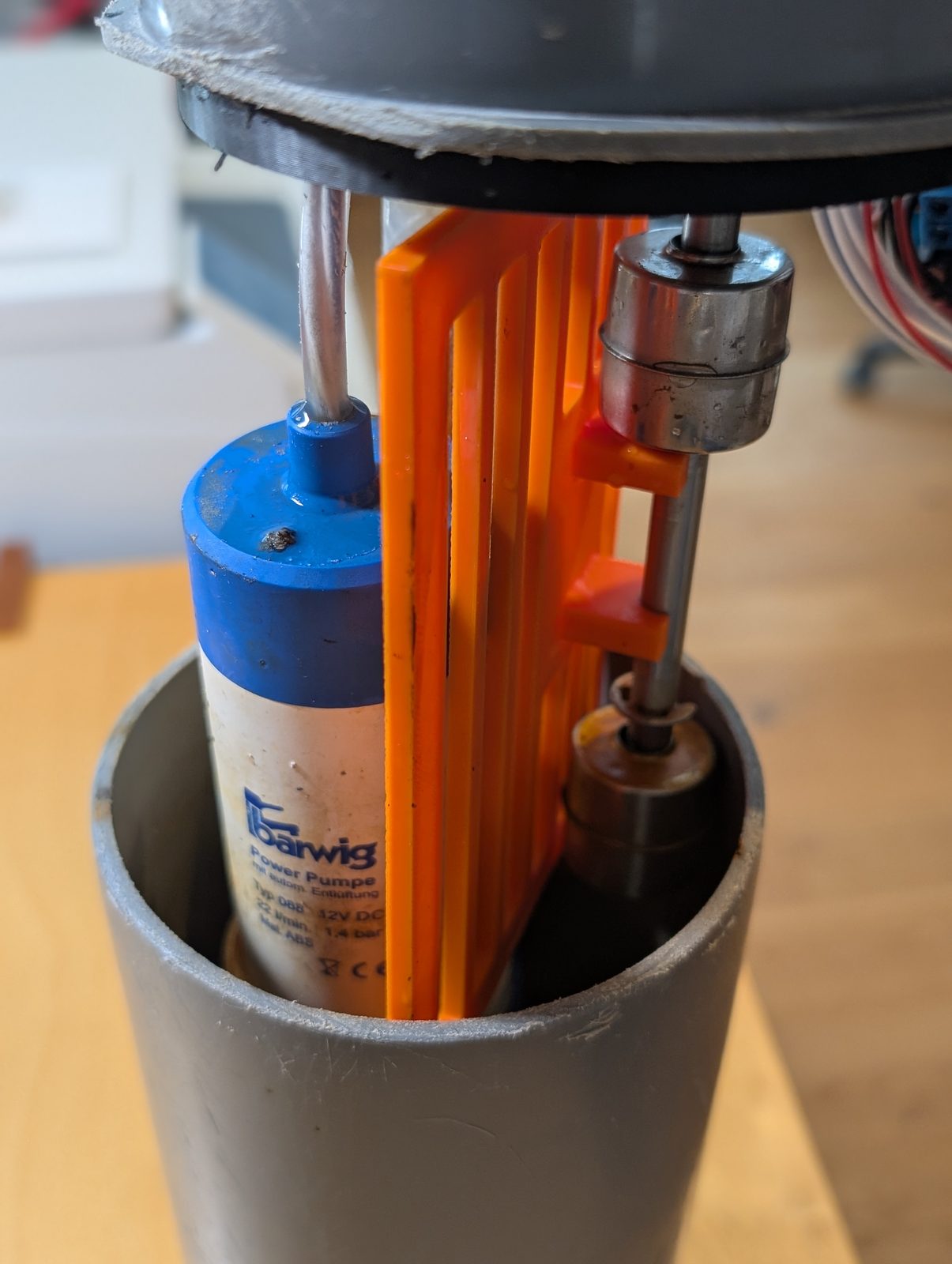 The prototype internals — orange divider, pump and float switch inside the grey pipe